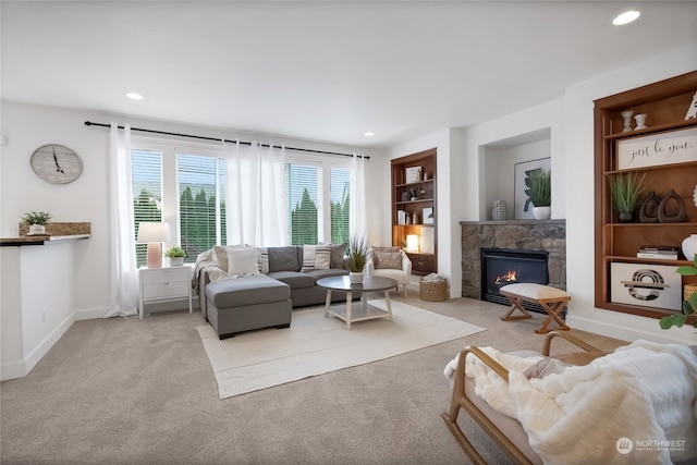 carpeted living room featuring a stone fireplace and built in features