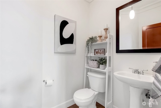 half bathroom featuring baseboards, a sink, and toilet