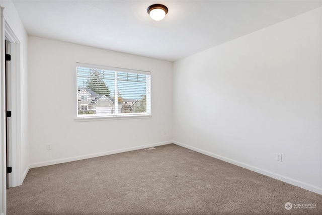 spare room featuring carpet floors, visible vents, and baseboards