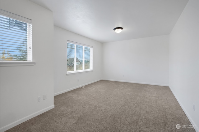 carpeted empty room featuring baseboards