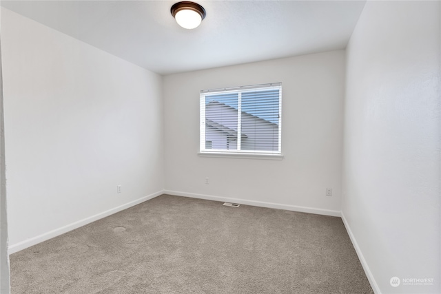 spare room featuring light carpet, visible vents, and baseboards