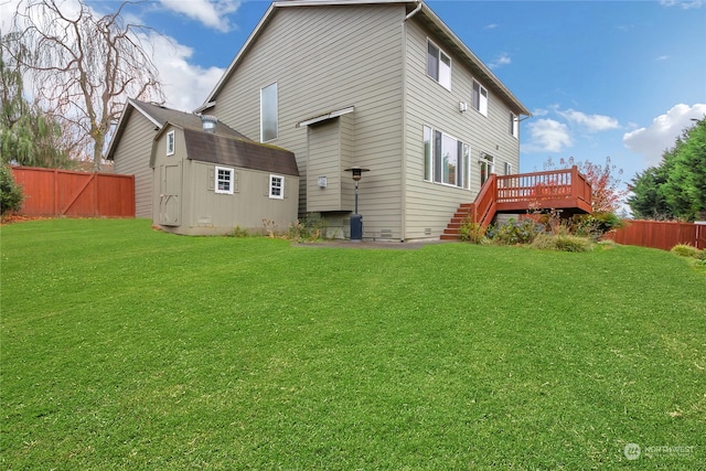 rear view of property with an outbuilding, fence, a deck, and a lawn