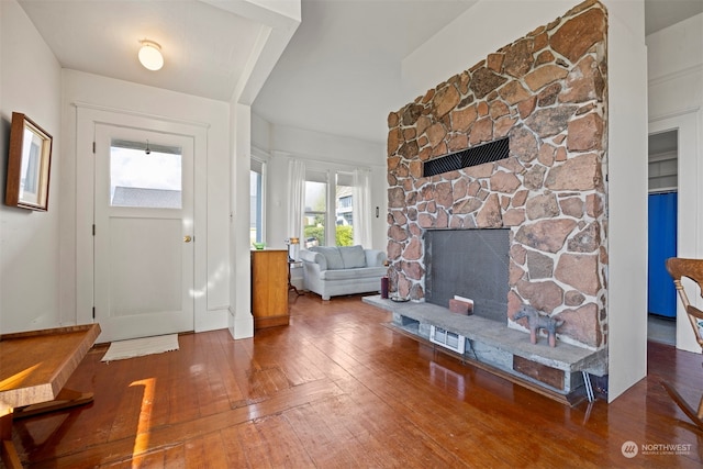 foyer entrance featuring plenty of natural light, a stone fireplace, and wood-type flooring