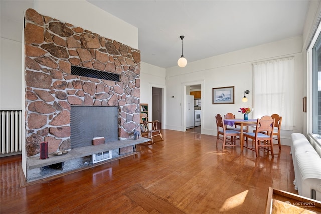 living room with radiator, a fireplace, and wood-type flooring