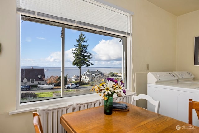 dining room with separate washer and dryer, a water view, and radiator