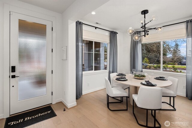 dining space with a chandelier, light wood-type flooring, visible vents, and baseboards