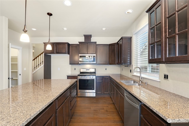 kitchen featuring sink, hanging light fixtures, stainless steel appliances, light stone counters, and dark hardwood / wood-style floors