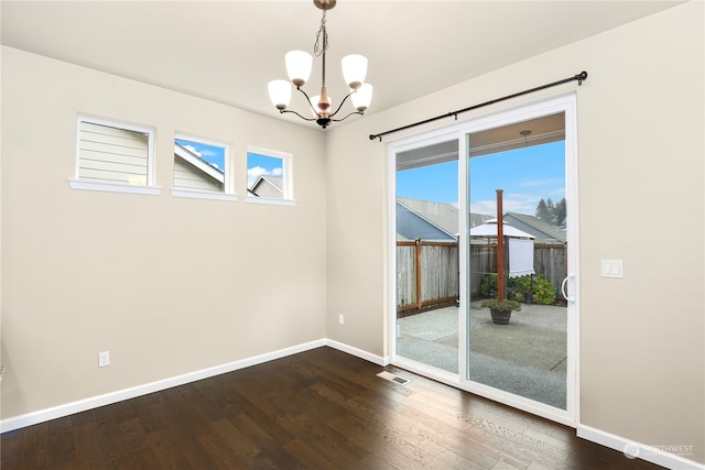 empty room with a chandelier and dark hardwood / wood-style floors