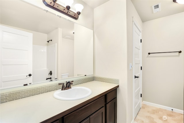 bathroom featuring decorative backsplash, a shower, vanity, and toilet