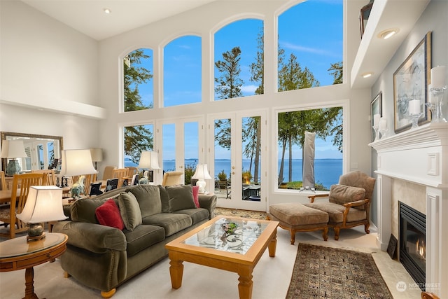 living room featuring a healthy amount of sunlight, a water view, and a towering ceiling