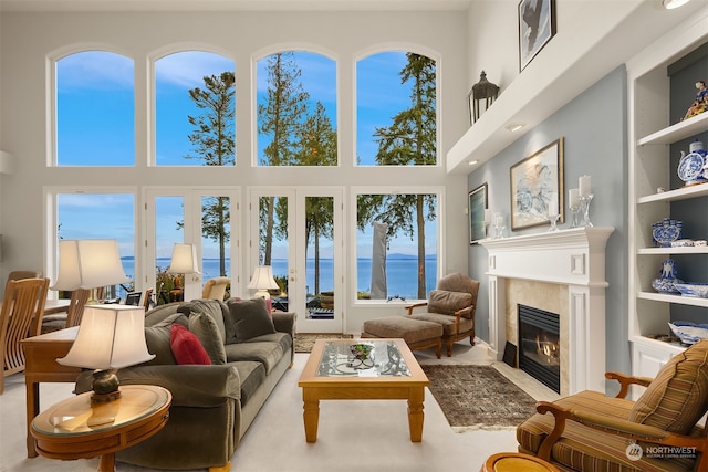 living room with a wealth of natural light, a water view, and a high ceiling