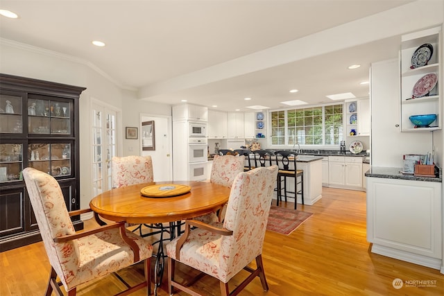 dining space featuring lofted ceiling, light wood-type flooring, and crown molding