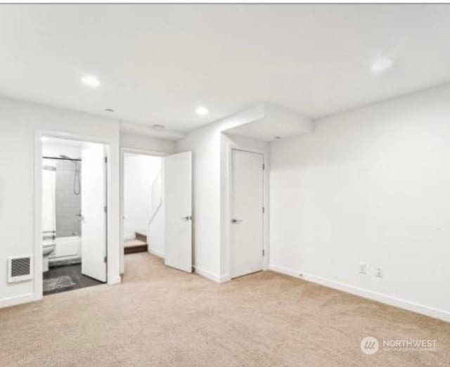 unfurnished bedroom featuring ensuite bathroom and light colored carpet