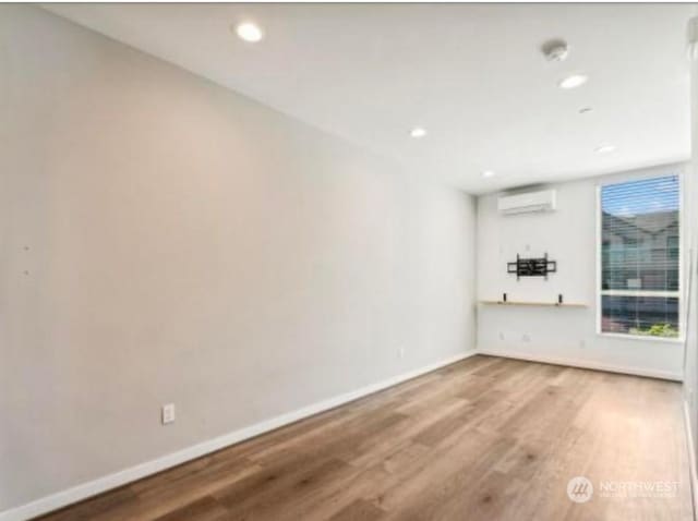 unfurnished room with hardwood / wood-style floors and a wall mounted AC