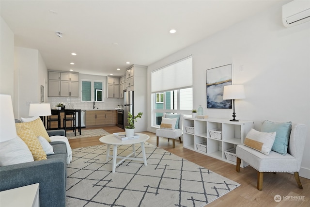 living room with light wood-type flooring, a wall unit AC, and sink