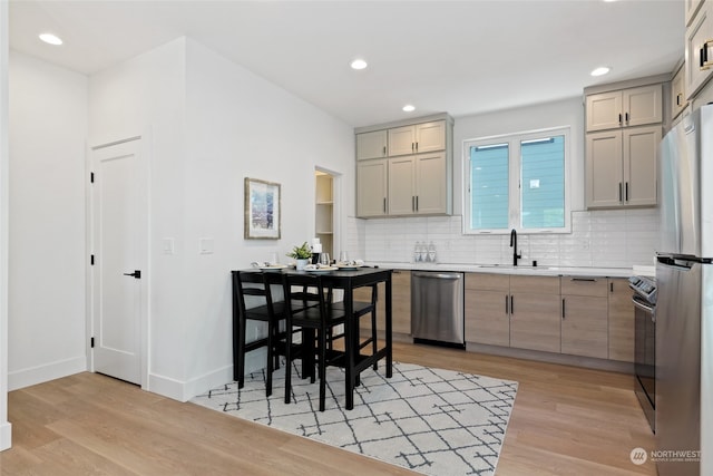 kitchen with tasteful backsplash, light hardwood / wood-style flooring, stainless steel appliances, and sink