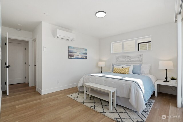 bedroom featuring a wall unit AC and light hardwood / wood-style flooring