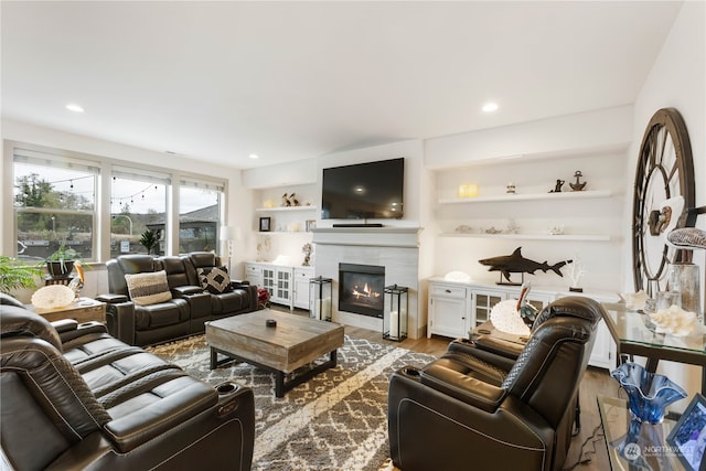 living room with built in shelves and light hardwood / wood-style flooring