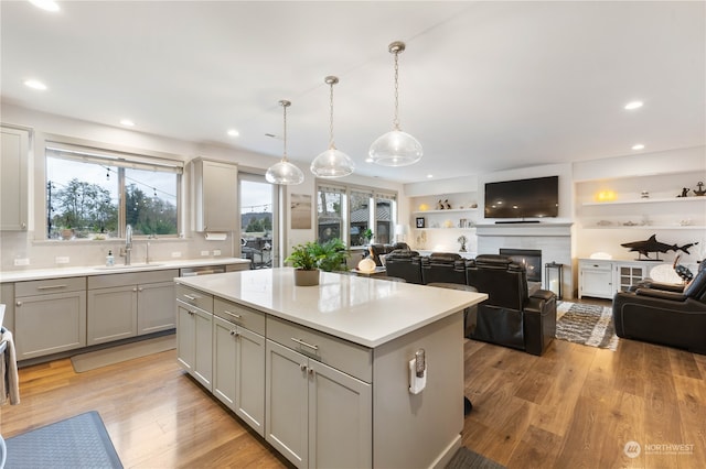 kitchen featuring pendant lighting, gray cabinets, a kitchen island, and light hardwood / wood-style floors