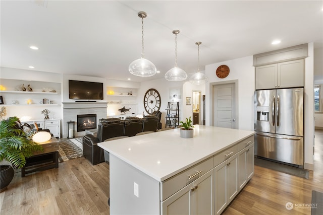 kitchen featuring stainless steel fridge with ice dispenser, a center island, pendant lighting, and light hardwood / wood-style flooring