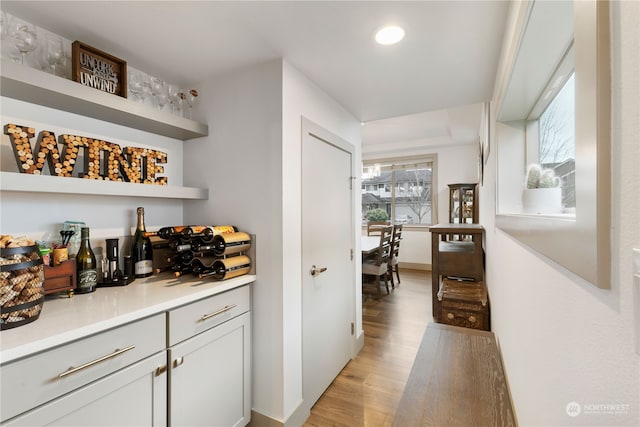 bar with white cabinets and light wood-type flooring