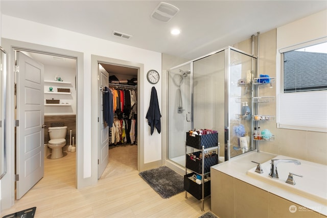 bathroom featuring shower with separate bathtub and toilet