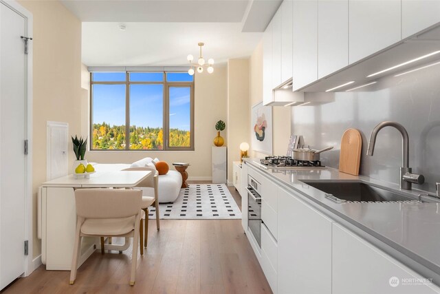 kitchen featuring sink, stainless steel appliances, hanging light fixtures, and white cabinets