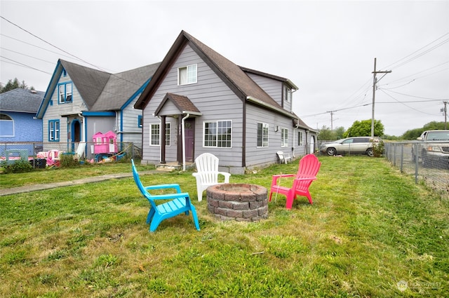 rear view of house with a yard and a fire pit