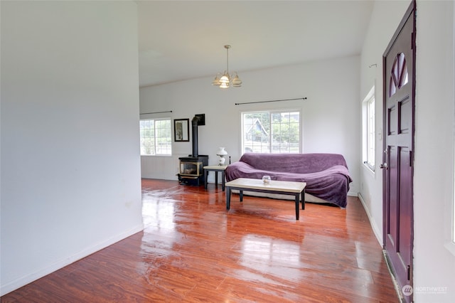 living room featuring hardwood / wood-style floors, a notable chandelier, a healthy amount of sunlight, and a wood stove