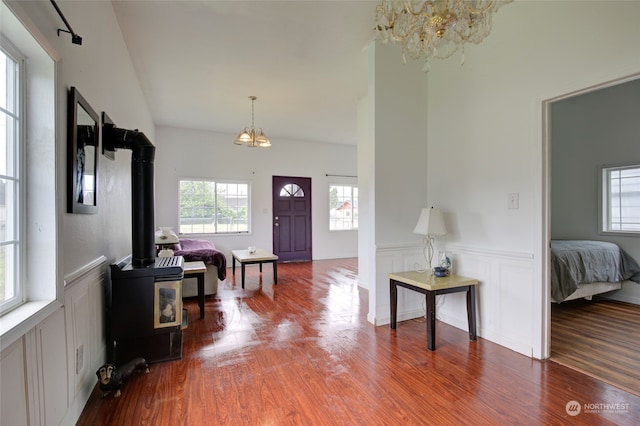 entryway with a chandelier, hardwood / wood-style flooring, and a wood stove