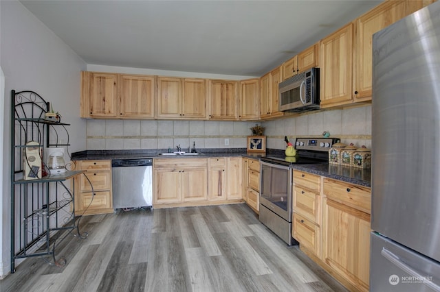 kitchen featuring sink, tasteful backsplash, light hardwood / wood-style flooring, light brown cabinetry, and appliances with stainless steel finishes