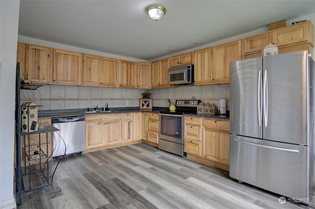 kitchen with backsplash, sink, light hardwood / wood-style flooring, light brown cabinetry, and appliances with stainless steel finishes