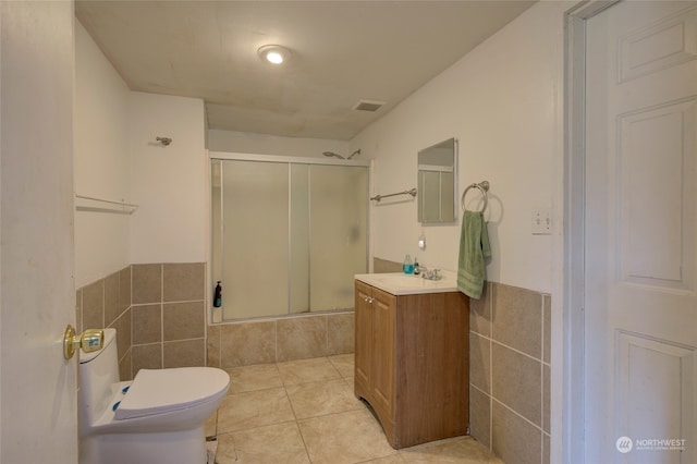 bathroom featuring toilet, vanity, tile patterned floors, and tile walls