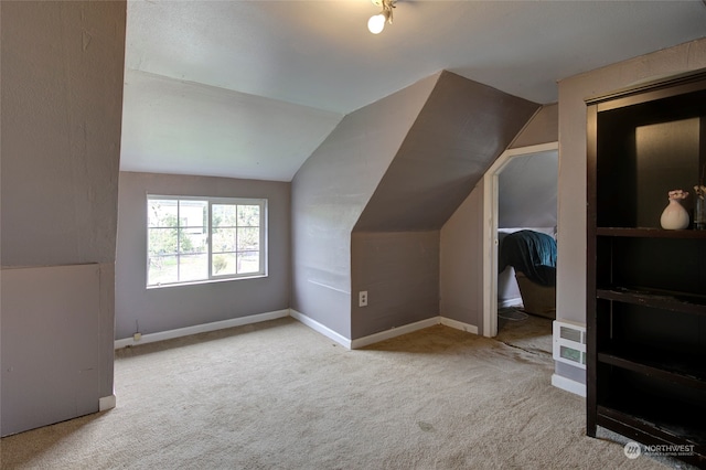 bonus room with light colored carpet and vaulted ceiling