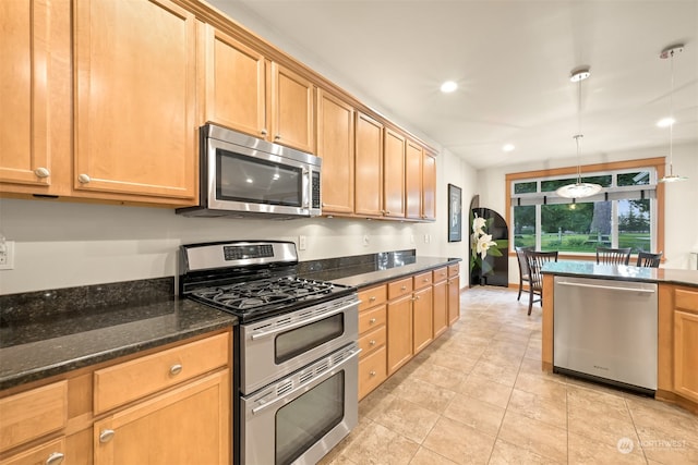 kitchen featuring light tile patterned floors, stainless steel appliances, hanging light fixtures, and dark stone counters