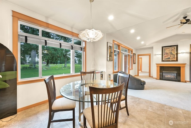 carpeted dining area featuring ceiling fan with notable chandelier and vaulted ceiling