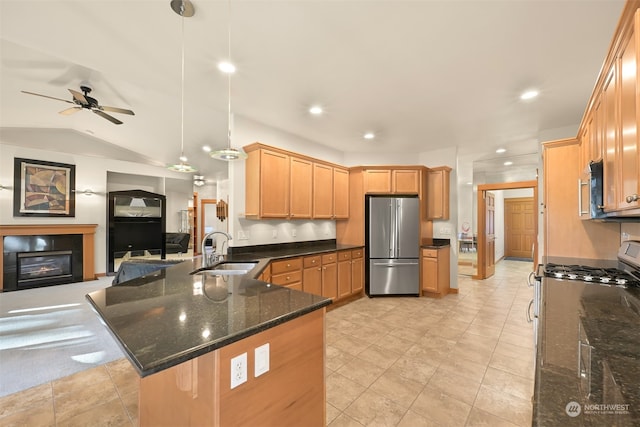 kitchen featuring appliances with stainless steel finishes, dark stone counters, vaulted ceiling, sink, and pendant lighting