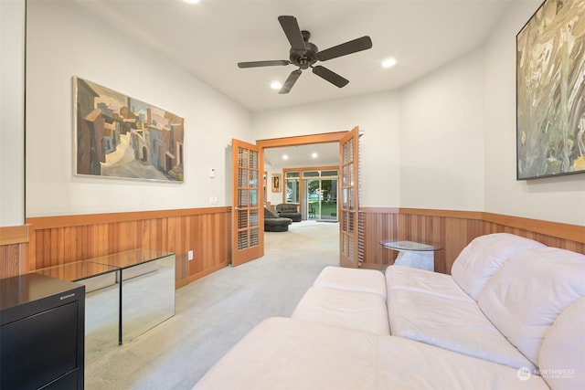 living room featuring ceiling fan, light carpet, and wooden walls