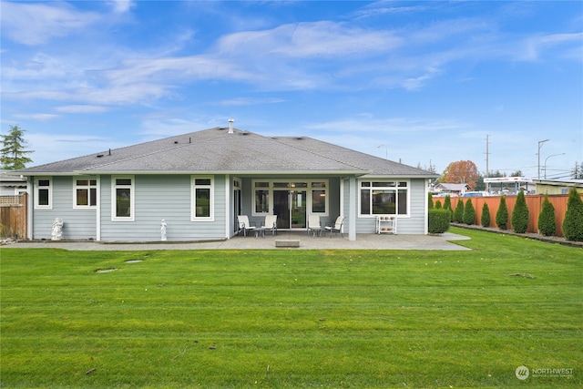 back of property with a lawn and a patio