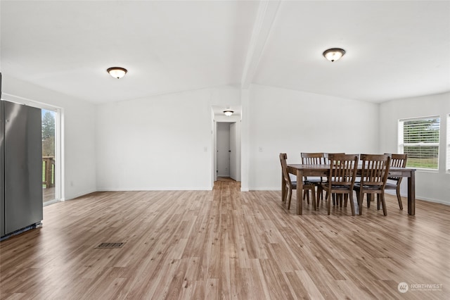 dining room featuring lofted ceiling with beams and light hardwood / wood-style floors