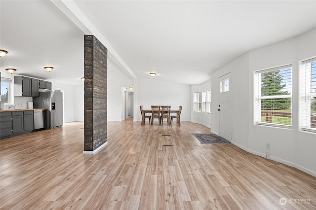 foyer entrance with light hardwood / wood-style floors, vaulted ceiling, sink, and decorative columns