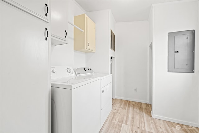 clothes washing area featuring cabinets, electric panel, washer and dryer, light wood-type flooring, and ornamental molding