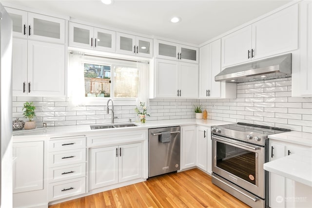 kitchen featuring white cabinetry, sink, backsplash, light hardwood / wood-style floors, and appliances with stainless steel finishes