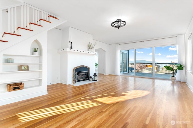 unfurnished living room with hardwood / wood-style flooring and built in shelves