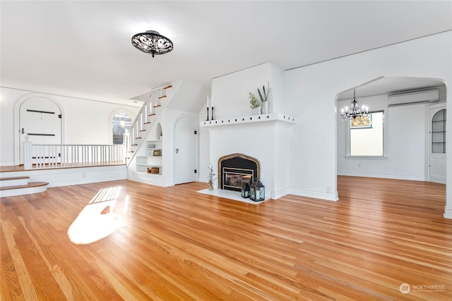 unfurnished living room featuring light hardwood / wood-style floors and an AC wall unit