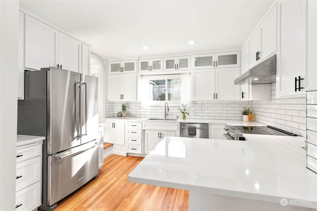 kitchen featuring white cabinetry, sink, backsplash, light hardwood / wood-style floors, and appliances with stainless steel finishes