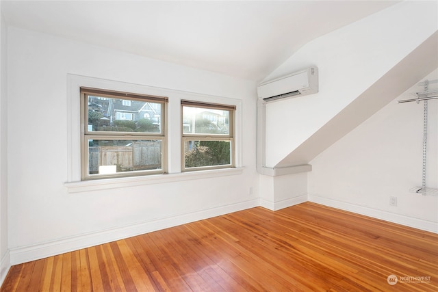 bonus room featuring hardwood / wood-style floors, a wall mounted AC, and lofted ceiling