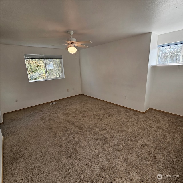 empty room featuring carpet flooring, ceiling fan, and a healthy amount of sunlight