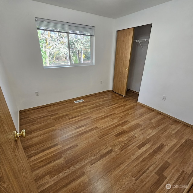 unfurnished bedroom featuring hardwood / wood-style flooring and a closet