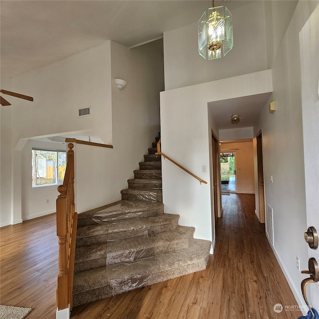 stairs featuring hardwood / wood-style floors and a high ceiling